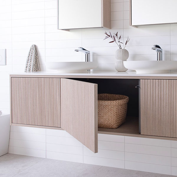 ADP Clifton wall-hung vanity in coastal oak with Caesarstone top, open door and twin basins in a bathroom setting