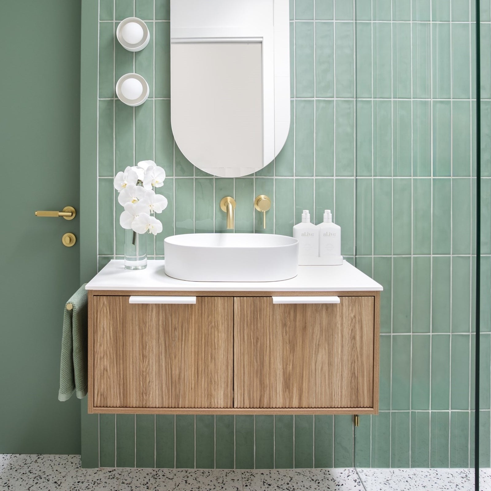 ADP Clifton wall-hung ensuite vanity in woodgrain with white top and round basin, shown in a green tiled bathroom setting