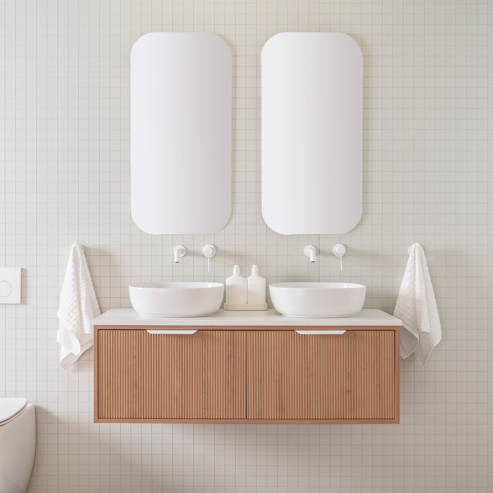 ADP Clifton wall-hung vanity with woodgrain drawers and white Durasein top, shown in a bathroom with dual basins