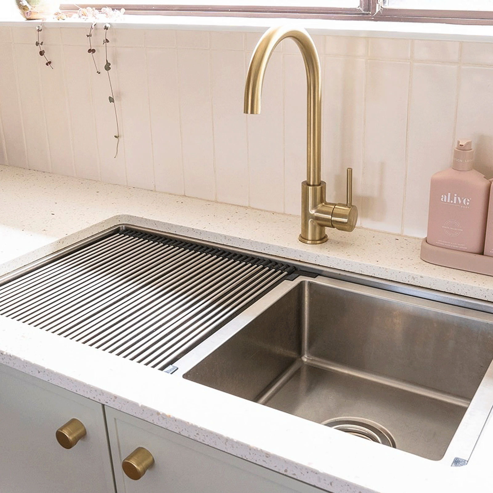 ADP Clovelly stainless steel kitchen sink with roll-up drainer and brass gooseneck mixer in a benchtop setting