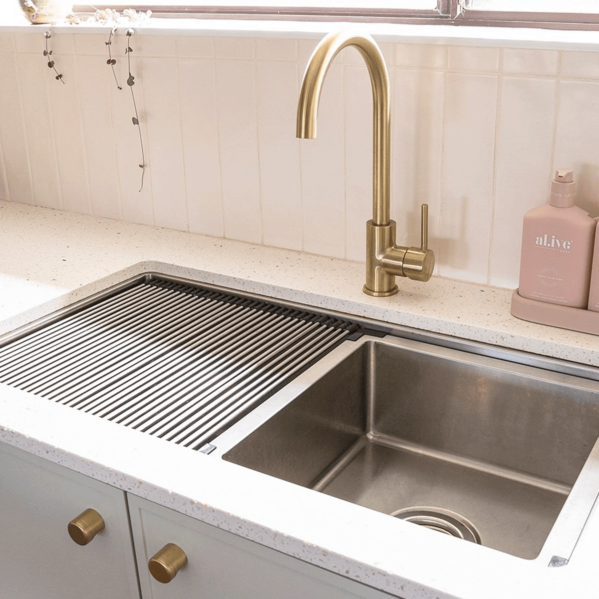 ADP Clovelly stainless steel kitchen sink with roll-up drainer and brass gooseneck mixer in a benchtop setting