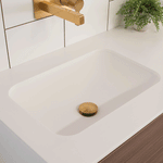 ADP Glory matte white rectangular under counter basin installed beneath a white benchtop with gold tapware and waste grate
