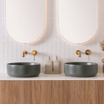 Two matte forest green ADP round above-counter basins on a timber vanity in a twin-basin bathroom setting