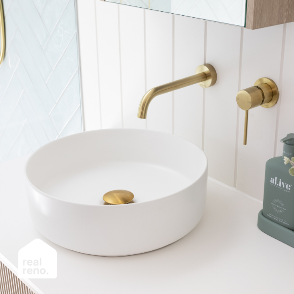 ADP Margot round above counter basin in matte white with gold waste, shown on a vanity with brass tapware and wall tiles