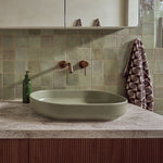 ADP Marilyn oval above counter basin in matte olive on a bathroom vanity with wall-mounted tapware and green tiled splashback