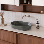 ADP Marilyn oval above-counter basin in matte forest green ceramic on a white vanity top