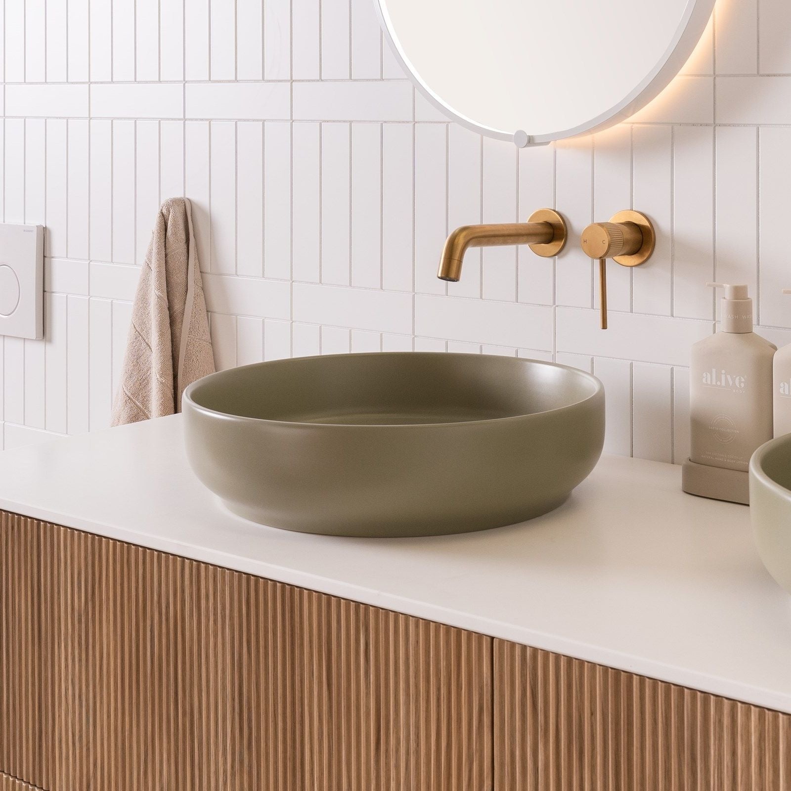 ADP Monroe round matte olive above counter basin on a white vanity with brass tapware, lifestyle view