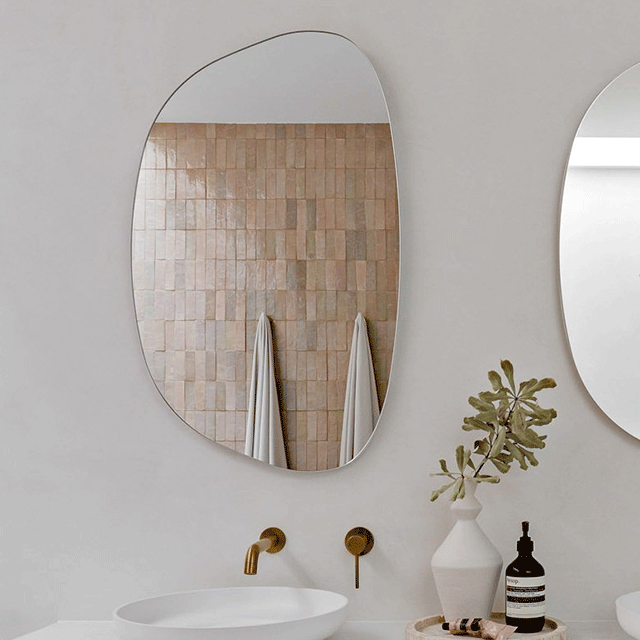 ADP Organic shaving cabinet with oval mirror, shown in a bathroom above a vanity with wall taps and decor