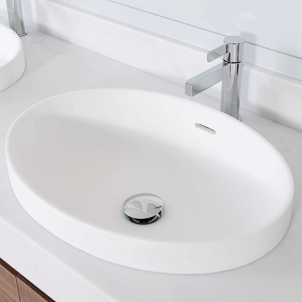 ADP Ozera matte white semi inset oval solid surface basin with overflow, shown installed on a vanity with chrome mixer tap