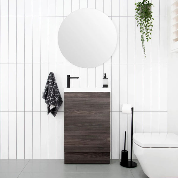 ADP Petite floor-standing vanity with kickboard, dark woodgrain finish and white top, in a compact bathroom setting