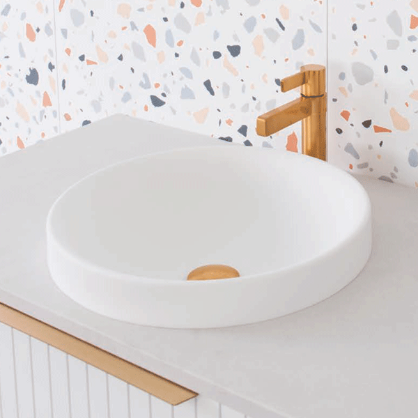 ADP Respect round semi-inset basin in gloss white solid surface, shown on a vanity with brushed gold tapware
