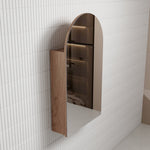 Aulic Canterbury Arch shaving cabinet in woodgrain finish, wall mounted with arched mirrored door against white tiled bathroom wall