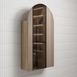 Aulic Canterbury arch shaving cabinet in Carita finish, with mirrored door and woodgrain side, wall mounted in bathroom tile.