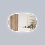 Aulic Valmont horizontal LED mirror with rounded corners and brushed bronze frame, lit against a grey wall