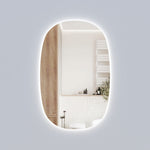 Aulic Valmont vertical LED mirror with rounded top and bottom, frameless oval-like shape, shown lit in a bathroom setting