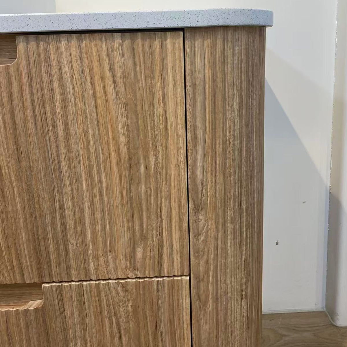 Aulic Varcelli floor standing vanity in woodgrain with a curved edge and pure white stone top, close-up detail