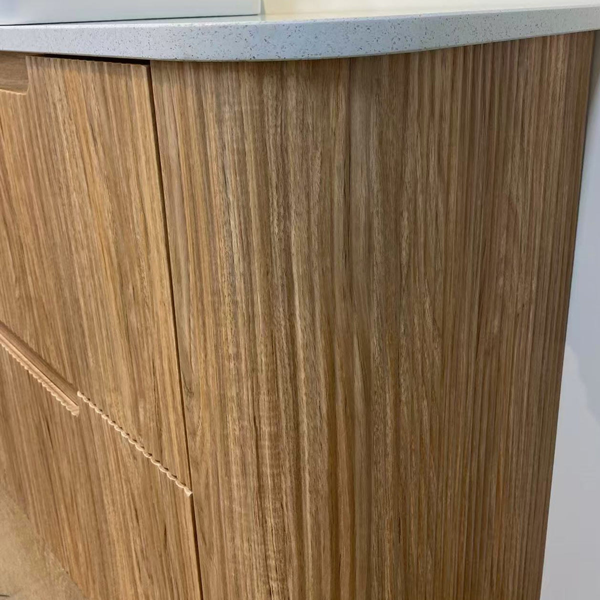 Aulic Varcelli floor standing vanity in woodgrain with Palis White stone top, close-up of curved end and fronts