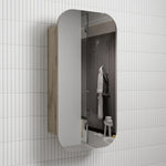 Aulic Vienna shaving cabinet with rounded-arch mirrored door, white front and woodgrain side, wall-mounted in bathroom