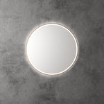 Aulic Windsor round LED mirror with brushed gold frame, front lit and backlit, mounted on a concrete wall