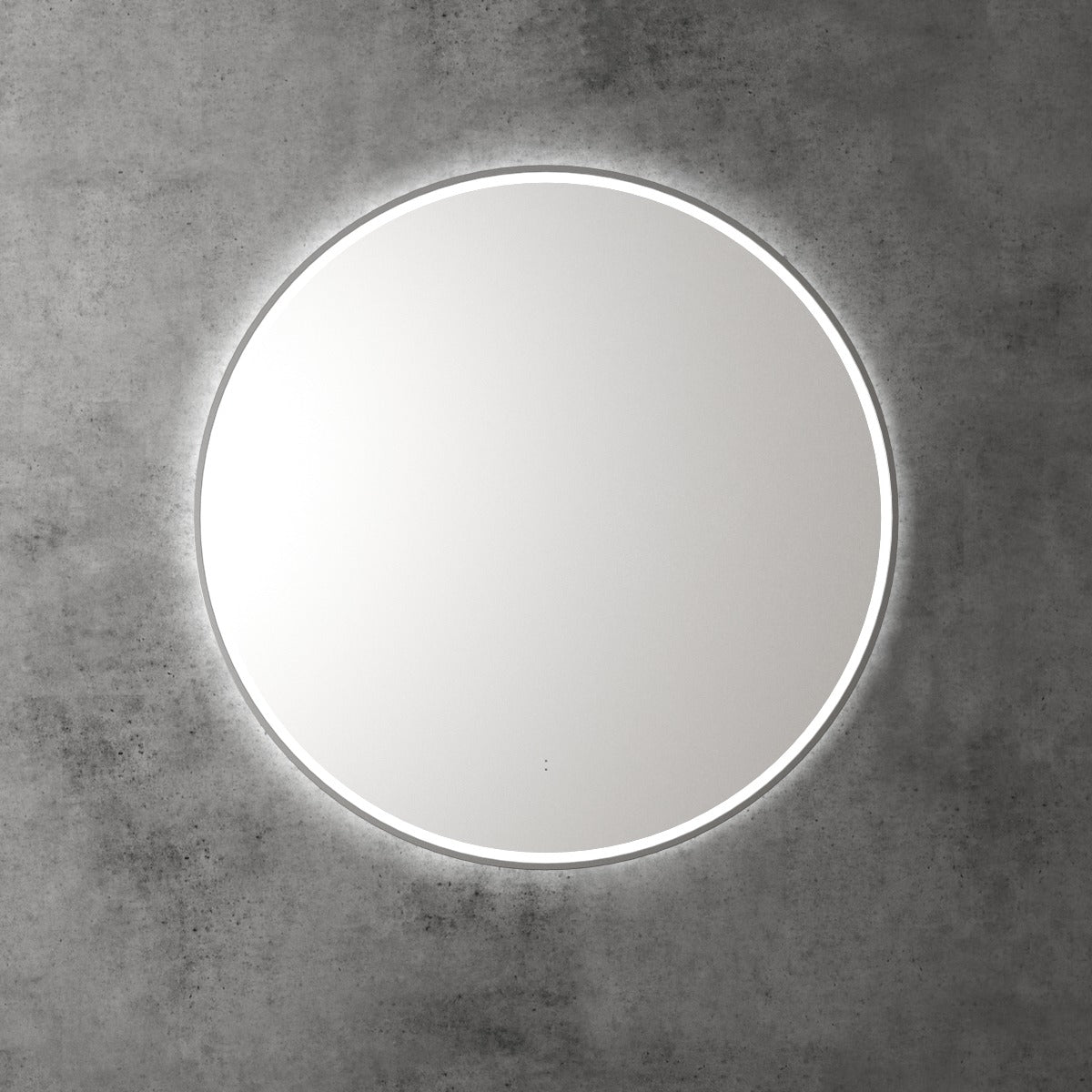 Aulic Windsor round LED mirror with slim silver frame and backlit glow, mounted on a concrete wall