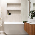 Bao Elegant white back-to-corner bath in a modern bathroom with wall niches and timber vanity