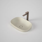Caroma Contura II matte clay oval inset basin with slim rim and flush waste, shown with a bronze mixer tap on a white background