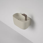 Caroma Contura II wall-hung hand basin in matte clay, oval ceramic with 1 tap hole and flush waste, shown on wall background
