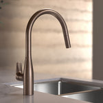 Caroma Contura II pull out sink mixer in brushed bronze, shown mounted above a kitchen sink with arched swivel spout