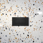 Caroma Invisi Series II rectangular dual flush plate in matte black, with two-button concealed toilet wall plate on terrazzo-style surface