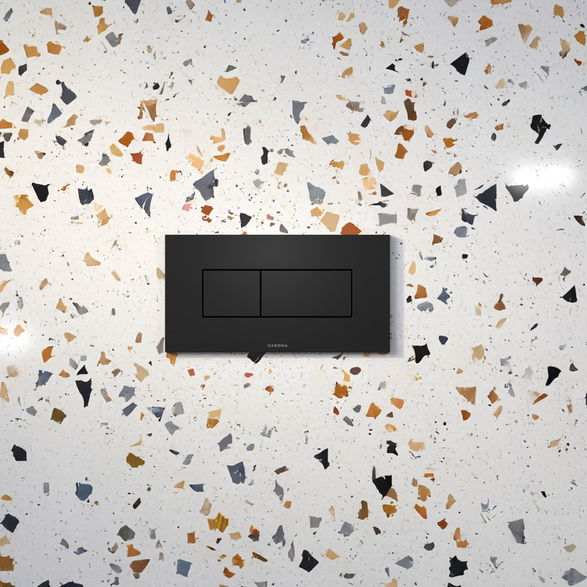 Caroma Invisi Series II rectangular dual flush plate in matte black, with two-button concealed toilet wall plate on terrazzo-style surface
