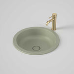 Caroma Liano II round matte green under/over counter basin with waste shown beside a gold tap