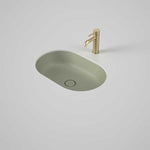 Caroma Liano II pill undercounter basin in matte green, oval ceramic vanity basin with matching waste and tap shown on a bench