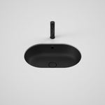 Caroma Liano II matte black oval under/over counter basin with overflow, shown from above with waste plug and dress ring