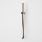 Caroma Liano II hand shower in brushed bronze with wall-mounted holder and hose on white background