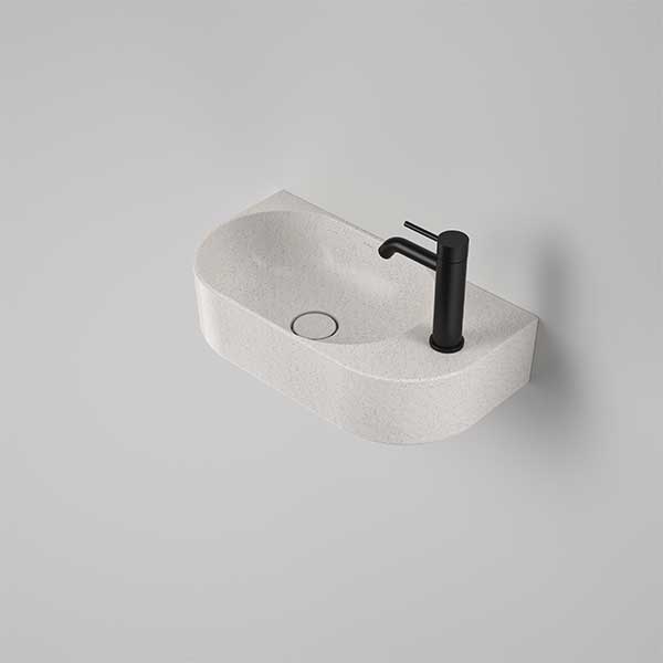 Caroma Liano II matte speckled wall basin, oval white ceramic hand basin with 1 tap hole shown angled on a grey background