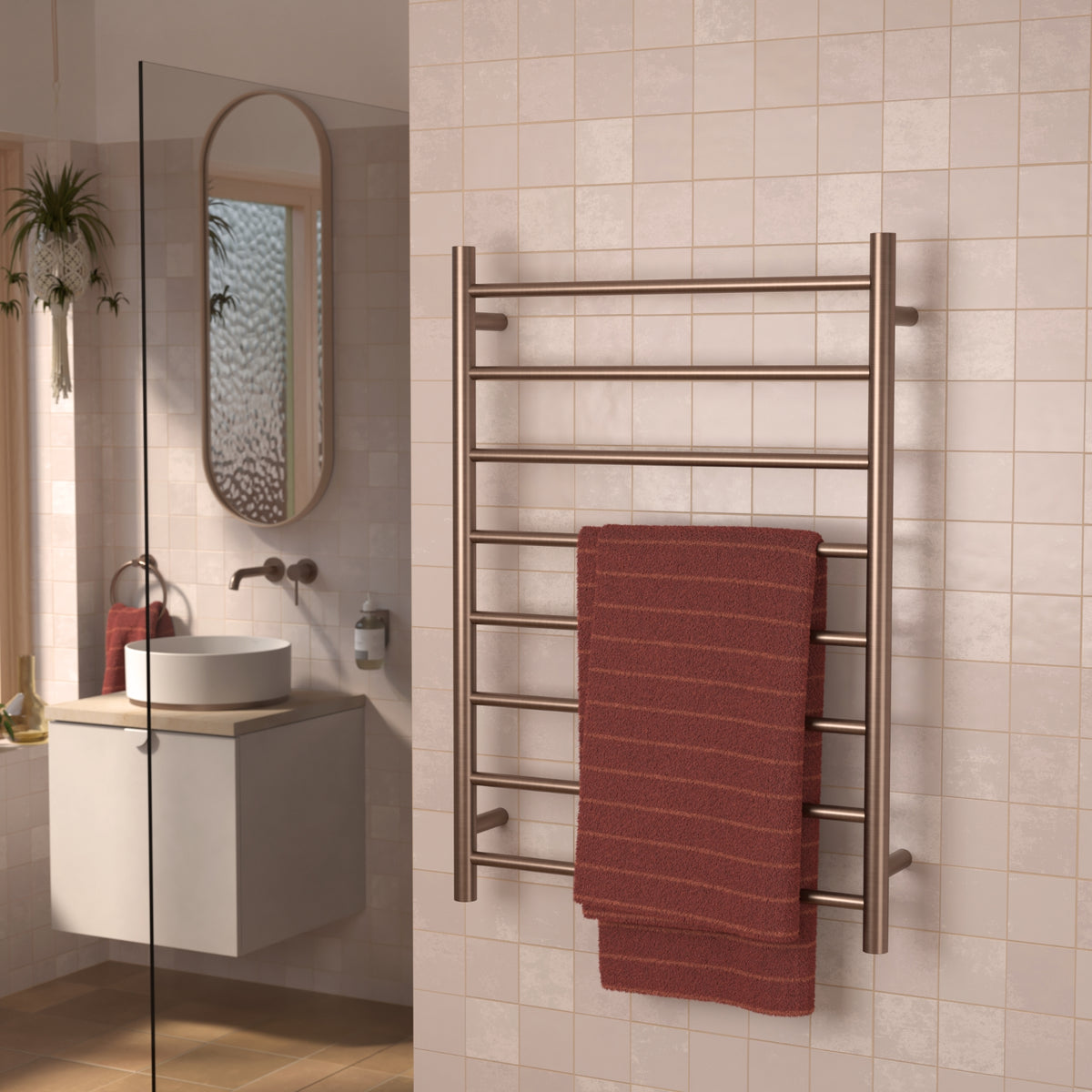 Caroma Liano II heated towel ladder in brushed bronze, wall mounted in a bathroom with a red towel.