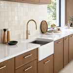 Caroma Liano II pull out sink mixer in brushed brass, shown installed over a kitchen sink in a modern benchtop setting