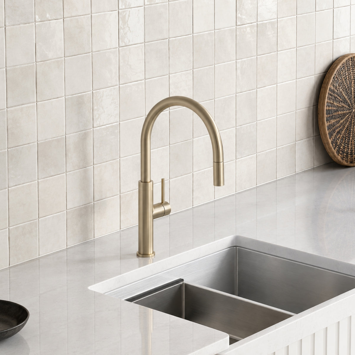 Caroma Liano II brushed brass pull-out sink mixer over stainless steel kitchen sink on light tiled splashback