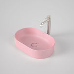Caroma Liano II pill above counter basin in matte pink, oval ceramic basin with matching waste and tap shown on grey background