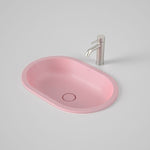 Caroma Liano II pink oval basin with slim rim and matching waste, shown with a brushed silver mixer tap on a grey surface