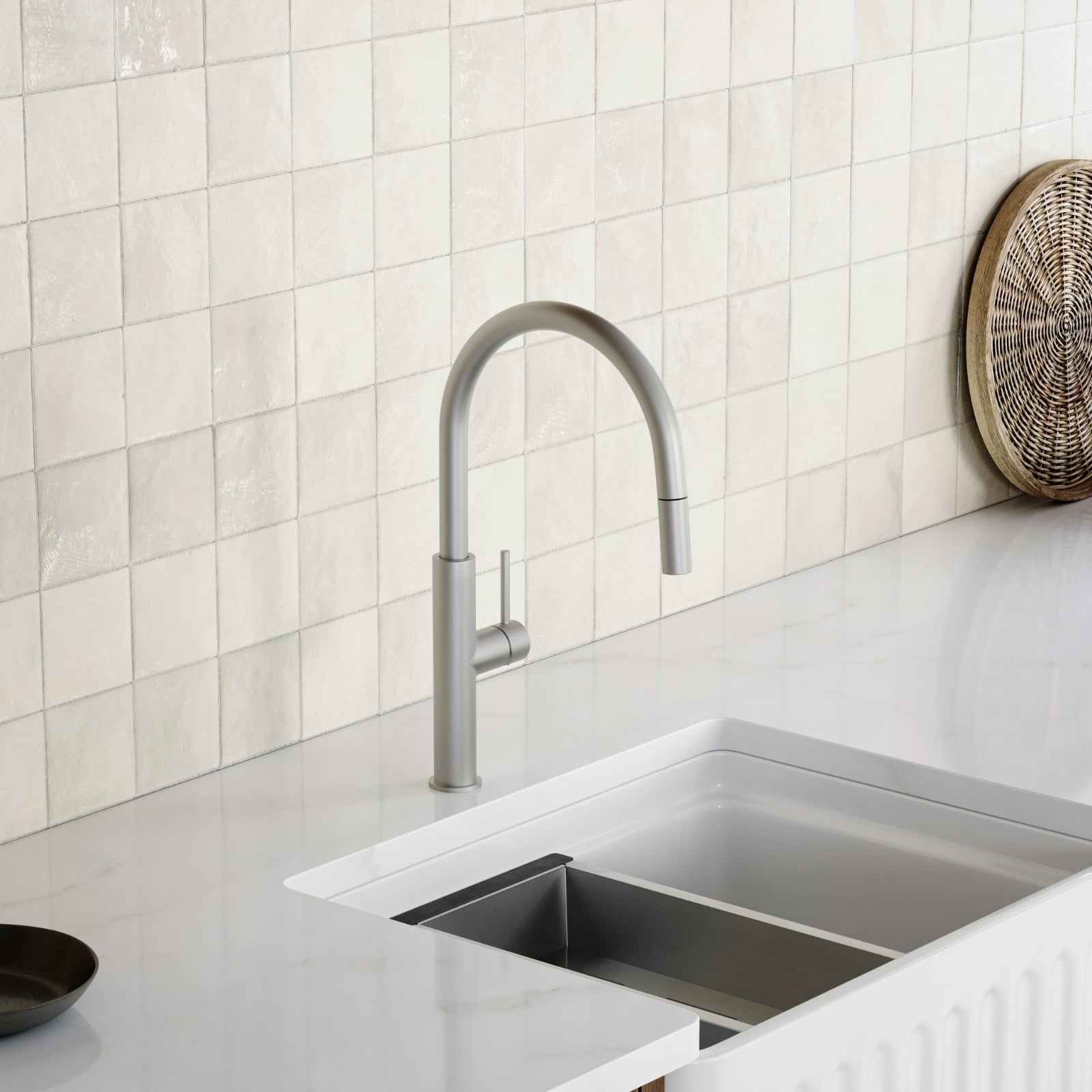 Caroma Liano II pull out sink mixer in brushed nickel over a white kitchen sink and tiled splashback