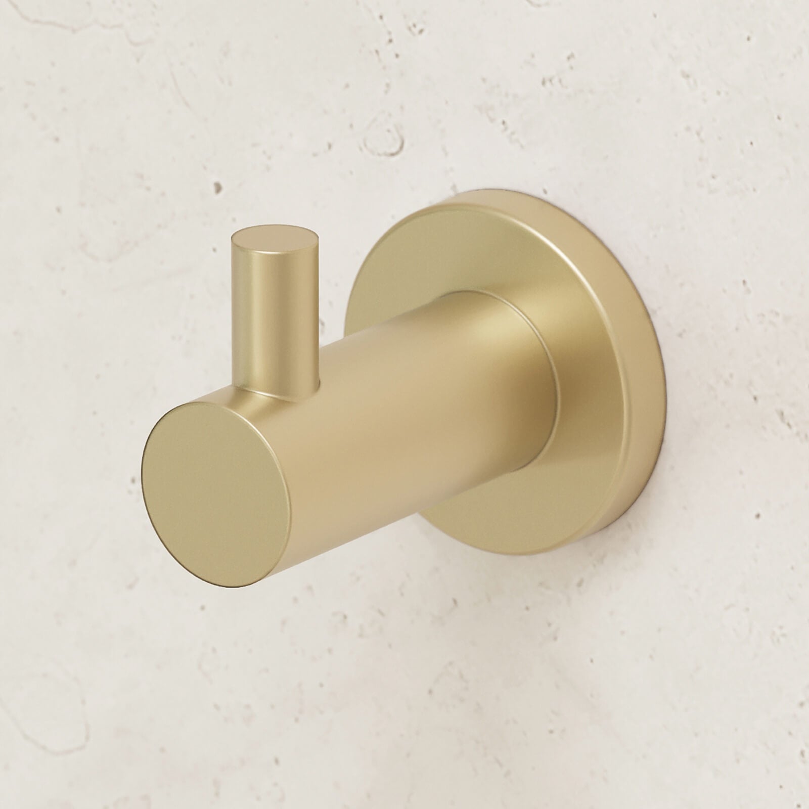 Caroma Liano II robe hook in brushed brass, wall-mounted on a light stone bathroom wall