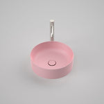 Caroma Liano II round above counter basin in matte pink, shown from above with matching waste and tapware slot behind
