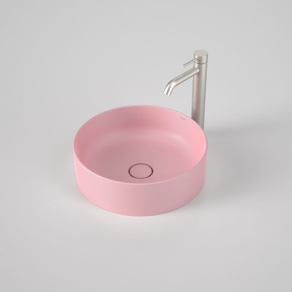 Caroma Liano II round above counter basin in matte pink, shown with mixer tap on a light grey background