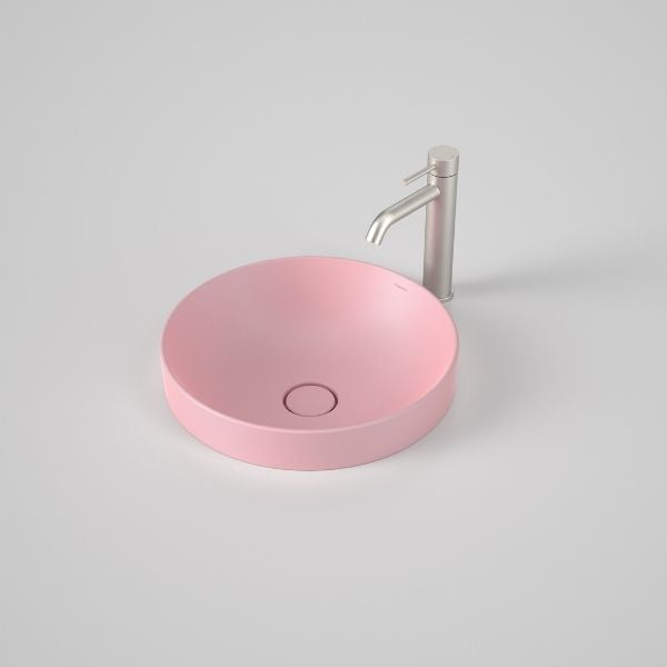Caroma Liano II round inset basin in matte pink with matching waste, shown with chrome tap on white background
