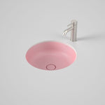 Caroma Liano II round under/over counter basin in matte pink with matching pop-up waste, shown with chrome mixer tap.