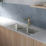 Caroma Luna II brushed brass sink mixer mounted above a double kitchen sink in a modern benchtop setting