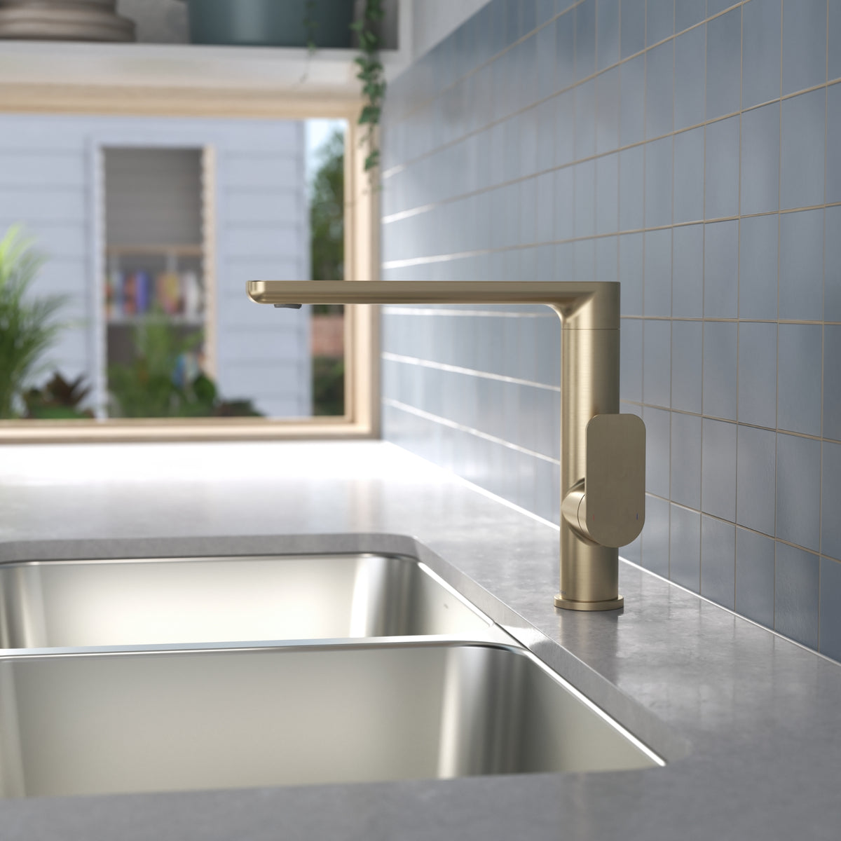 Caroma Luna II brushed brass sink mixer on a kitchen benchtop beside a stainless steel sink, side view