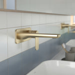 Caroma Luna II wall basin/bath mixer in brushed brass, wall-mounted over a tiled bathroom basin, side view