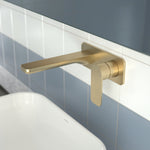 Caroma Luna II wall basin/bath mixer in brushed brass, wall-mounted above a basin in a tiled bathroom.